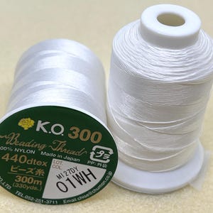 May include: A white spool of K.O. 300 Beading Thread, made in Japan. The spool is labelled with the text "440dtex", "300m (330yds.)", "M1 27DY", and "01WH".