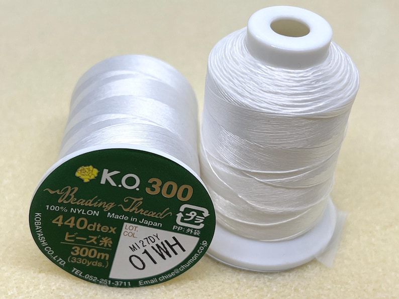 May include: A white spool of K.O. 300 Beading Thread, made in Japan. The spool is labelled with the text "440dtex", "300m (330yds.)", "M1 27DY", and "01WH".