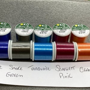 May include: Six spools of beading thread in various colours, including clear blue, smoke green, turquoise, scarlet pink, and orange. Each spool is labelled with the brand "KO Beading Thread" and a lot number.