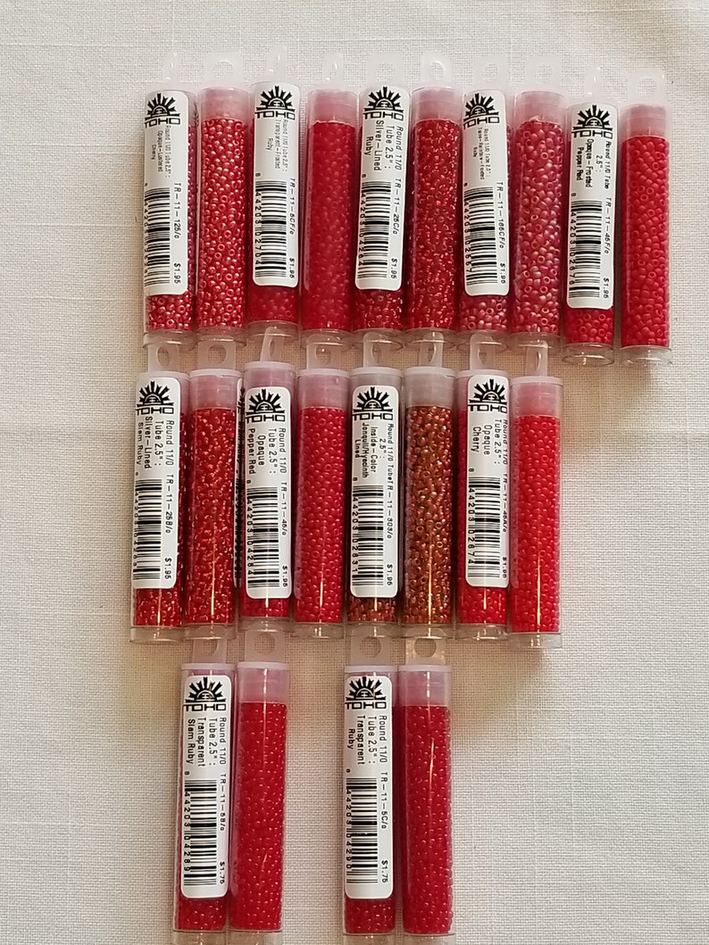 Pode incluir: Uma cole&ccedil;&atilde;o de 15 pequenos tubos de contas de sementes vermelhas e marrons. Os tubos s&atilde;o etiquetados com a marca TOHO e o tamanho e a cor das contas. As contas s&atilde;o redondas e t&ecirc;m um acabamento brilhante.