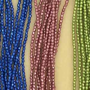 May include: Three strands of metallic beads in blue, pink, and green. The beads are small and have a faceted, shiny finish.