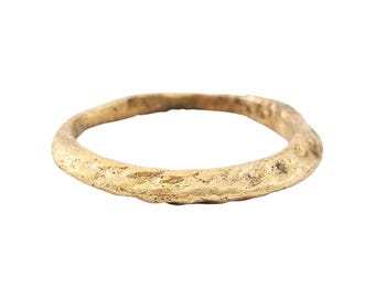 May include: A simple gold band ring with a textured surface.