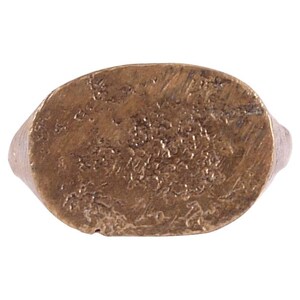 May include: A gold-toned oval ring with a detailed design on the top. The design is intricate and appears to be made of small, raised dots.