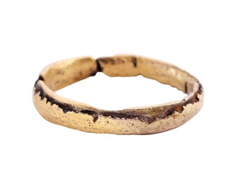 May include: A simple gold band ring with a worn, textured surface.