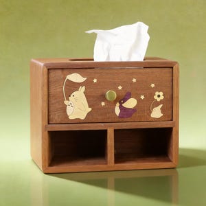 K&ouml;nnte beinhalten: Braune Holz-Taschentuchbox mit Schublade und zwei F&auml;chern. Die Box ist mit Ausschnitten von Zeichentrickfiguren und Sternen verziert. Ein wei&szlig;es Taschentuch ragt aus der oberen &Ouml;ffnung heraus. Die Schublade hat einen goldfarbenen Knopf.