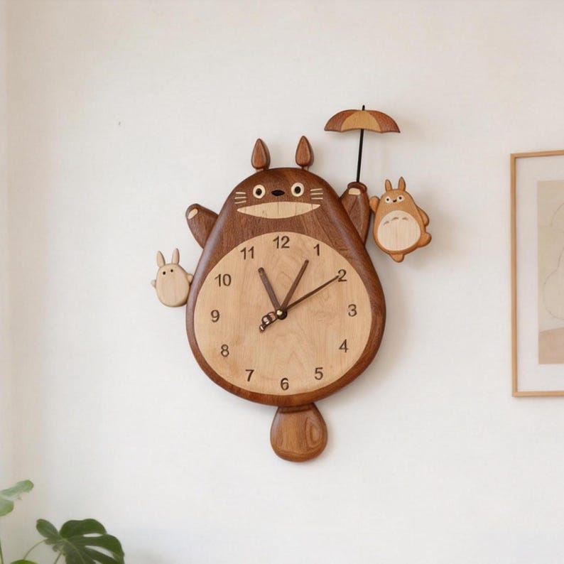 May include: A wooden wall clock shaped like a large brown creature with pointed ears, holding a small umbrella. The clock face is light wood with black numerals from 1 to 12 and dark hands. Two smaller creatures are attached to the sides.