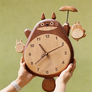 Puede incluir: Un reloj de pared de madera con forma de criatura grande de color marrón oscuro, con esfera de madera clara, números negros y manecillas oscuras. El reloj presenta dos figuras pequeñas de madera clara a los lados, una con un paraguas.