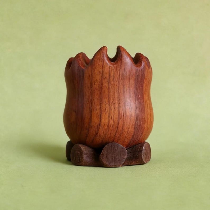 May include: A handcrafted wooden vase with a unique, wavy rim. The vase is a rich, warm brown color and sits on a small, round wooden base. The wood grain is visible, adding to the natural aesthetic. The vase is empty.