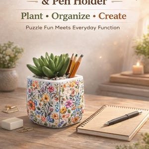 May include: A floral 3D puzzle plant pot and pen holder with a succulent plant and pencils. The pot has a colorful flower pattern. A notebook and pen are on the wooden surface. Text reads: "3D Puzzle Plant Pot & Pen Holder."