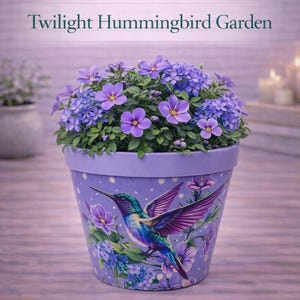 Puede incluir: Una maceta BloomShape Puzzle de color lavanda con un diseño de Twilight Hummingbird Garden. La maceta presenta una ilustración de colibrí con flores moradas y azules. La maceta está llena de flores moradas y follaje verde. Se muestra el texto "Twilight Hummingbird Garden".