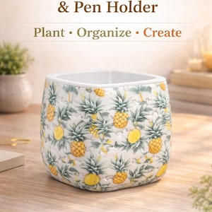 May include: A square, white-rimmed plant pot and pen holder with a repeating pattern of yellow pineapples and green leaves on a white background. Text on the image reads "3D Puzzle Plant Pot & Pen Holder" and "Golden Pineapple Garden."