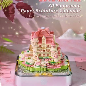 May include: A 3D paper sculpture calendar in the shape of a castle, with pink and white details. The calendar is on a light-up base and features the text "LOVE CASTLE" and "3D Panoramic Paper Sculpture Calendar".