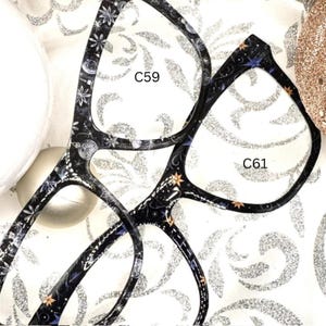 May include: Two pairs of black eyeglasses with a star and floral pattern. The lenses are clear. The frames are labeled C59 and C61.