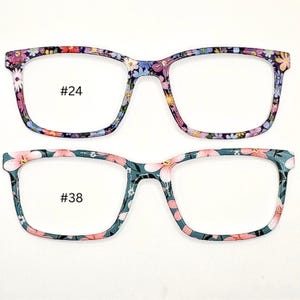 May include: Two pairs of eyeglasses with floral patterned frames. The top pair has a purple and pink floral pattern and the bottom pair has a teal and pink floral pattern. The top pair is labeled #24 and the bottom pair is labeled #38.