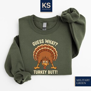 A green sweatshirt with a cartoon turkey and the text "Guess What? Turkey Butt!" printed on it.