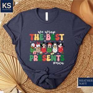 A dark blue t-shirt with a colorful graphic design featuring Disney characters and text, along with a straw hat and woven mat in the background.