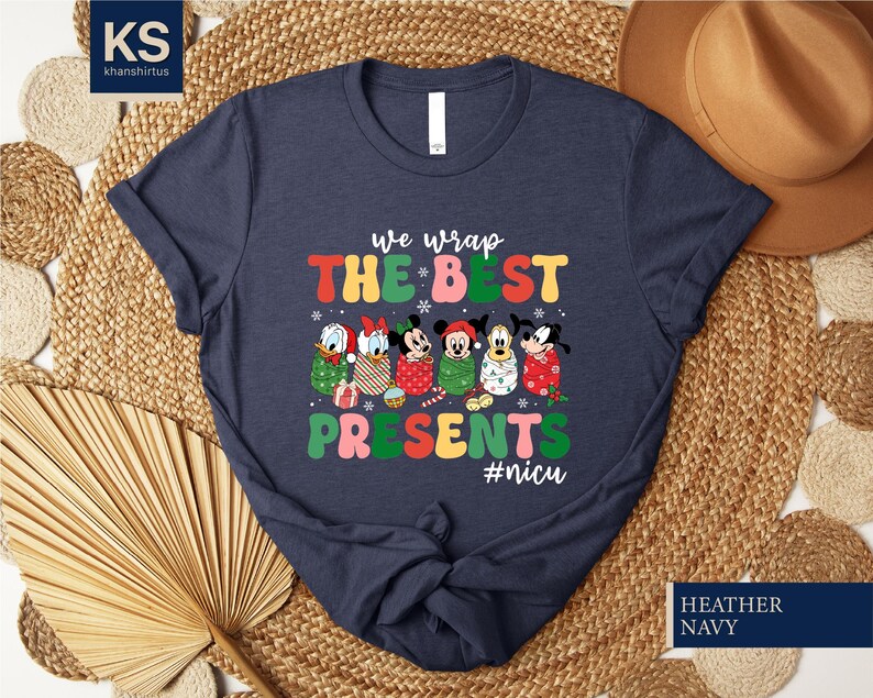 A dark blue t-shirt with a colorful graphic design featuring Disney characters and text, along with a straw hat and woven mat in the background.