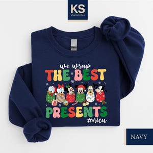 A navy blue sweatshirt with a colorful graphic design featuring Disney characters and the text "we wrap the best presents #nics".
