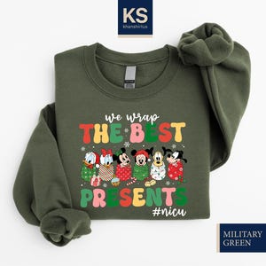 A green sweatshirt with a colorful graphic design featuring Disney characters and the text "We wrap the best presents #niscu" printed on it.