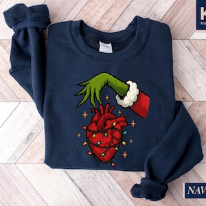 A navy blue sweatshirt with a graphic design depicting a hand holding a heart with Christmas lights around it.