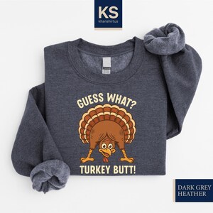 A gray sweatshirt with a graphic of a turkey and the text "Guess What? Turkey Butt!" printed on it.