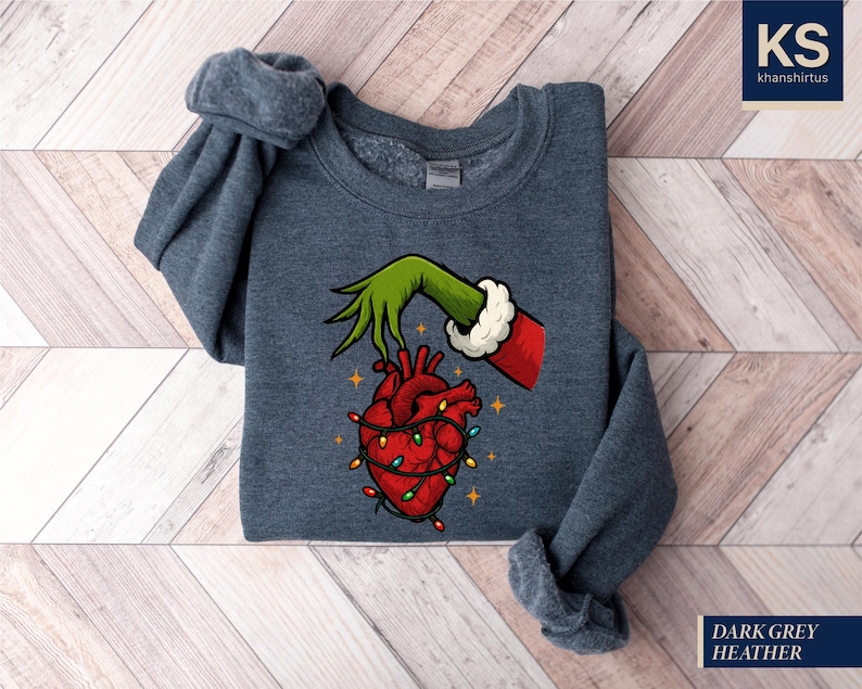 A gray sweatshirt with a graphic design depicting a hand holding a heart with Christmas lights around it.