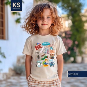 May include: A beige t-shirt with the words "I CAN BE" and other positive affirmations, along with colorful illustrations. The shirt is labeled "NATURAL" and has the brand logo "KS khanshirtus".