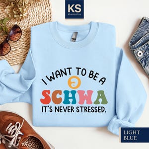 May include: Light blue sweatshirt with the text "I want to be a schwa it's never stressed." in colorful letters.
