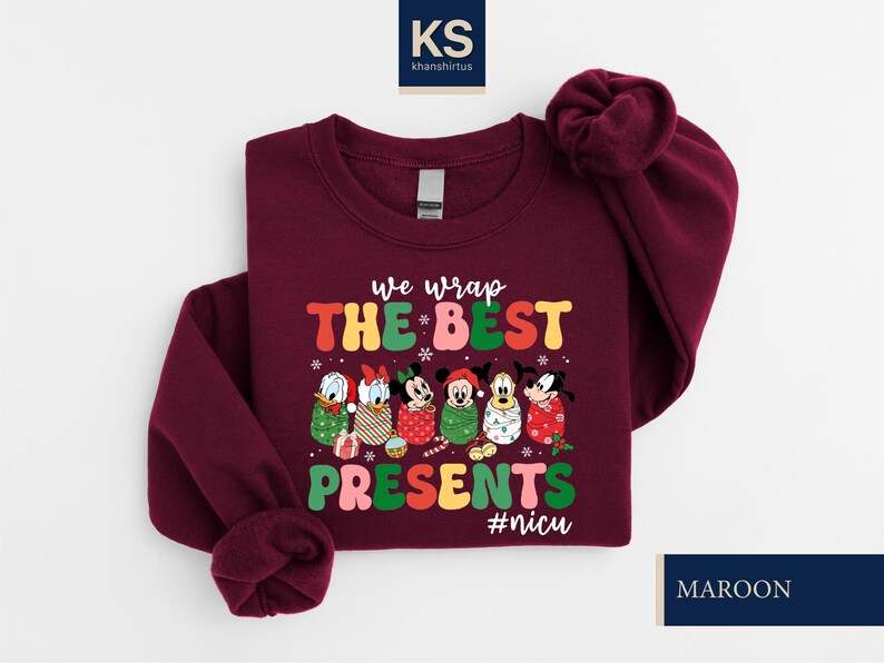 A burgundy-colored sweater with a Christmas-themed design featuring Disney characters and the text "we wrap the best presents #nuc".