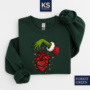 A green sweater with a graphic design depicting a hand holding a lit heart, surrounded by Christmas lights.