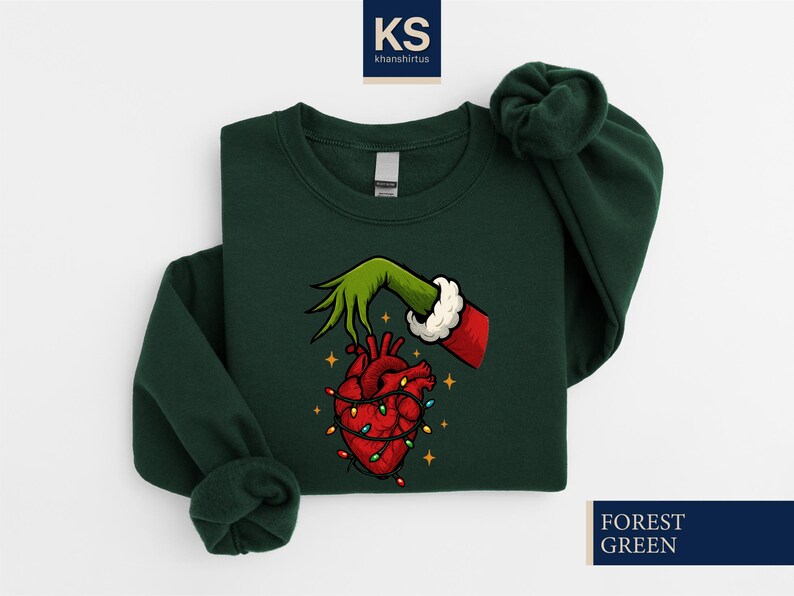 A green sweater with a graphic design depicting a hand holding a lit heart, surrounded by Christmas lights.