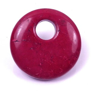 May include: A round, red, gemstone pendant with a hole in the center. The pendant has a marbled pattern and a smooth, polished finish.