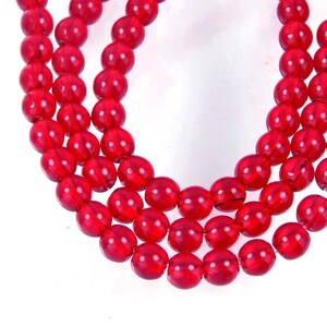 May include: A strand of bright red glass beads. The beads are round and have a smooth, glossy finish.