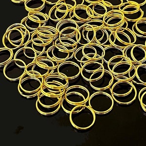 May include: A large pile of gold jump rings, a type of metal ring used in jewelry making.