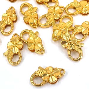 May include: A group of 15 gold-tone metal flower-shaped clasps. The clasps are designed to be used as jewelry making supplies.