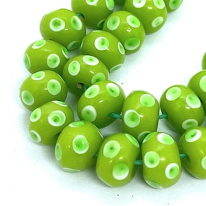 May include: A strand of green glass beads with white polka dots. The beads are round and have a glossy finish.