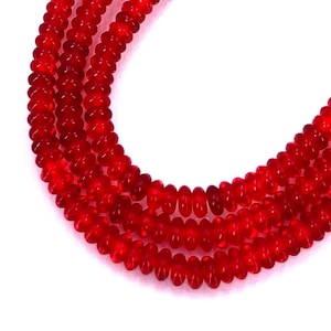 May include: A strand of bright red glass beads. The beads are round and have a smooth, polished finish.