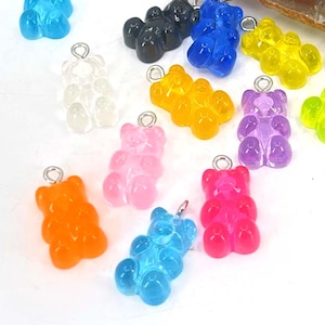 May include: Assortment of colorful gummy bear charms in various colors, including red, orange, yellow, green, blue, purple, pink, black, and clear. The charms are made of plastic and have a shiny finish.