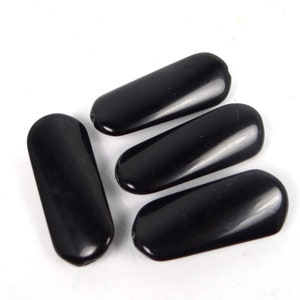 May include: Four black oval-shaped beads. The beads are smooth and glossy.