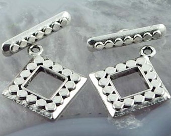 May include: Two silver-toned metal pendant charms with a square frame and a decorative border of small circles. Each charm has a bar with a row of small circles attached to the top.