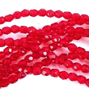 May include: A strand of red faceted glass beads. The beads are small and have a shiny finish.