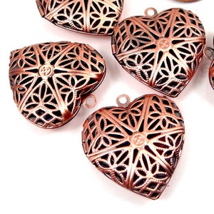 May include: Five copper-colored heart-shaped locket pendants with intricate filigree designs. Each pendant has a small loop at the top for attaching a chain or cord.