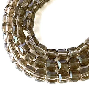 May include: A strand of brown faceted glass beads. The beads are square shaped and have a slight shimmer.