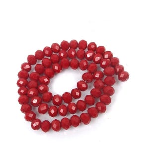 May include: A strand of red faceted glass beads. The beads are round and have a shiny finish.
