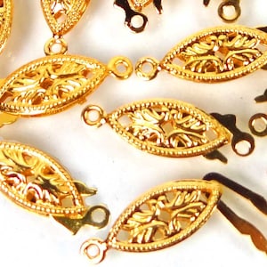 May include: Gold-toned metal clasps with an ornate design. Each clasp has a loop on one end and a hook on the other end.