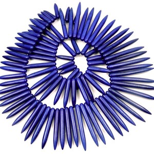 May include: A strand of dark blue gemstone beads, each bead is a long, thin, pointed shape. The beads are arranged in a circular pattern.