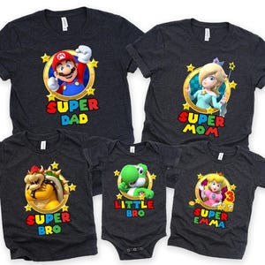 May include: A set of five gray t-shirts featuring characters from the Super Mario Bros. video game franchise. The shirts have different designs and text, including "Super Dad", "Super Mom", "Super Bro", "Little Bro", and "Super Emma".