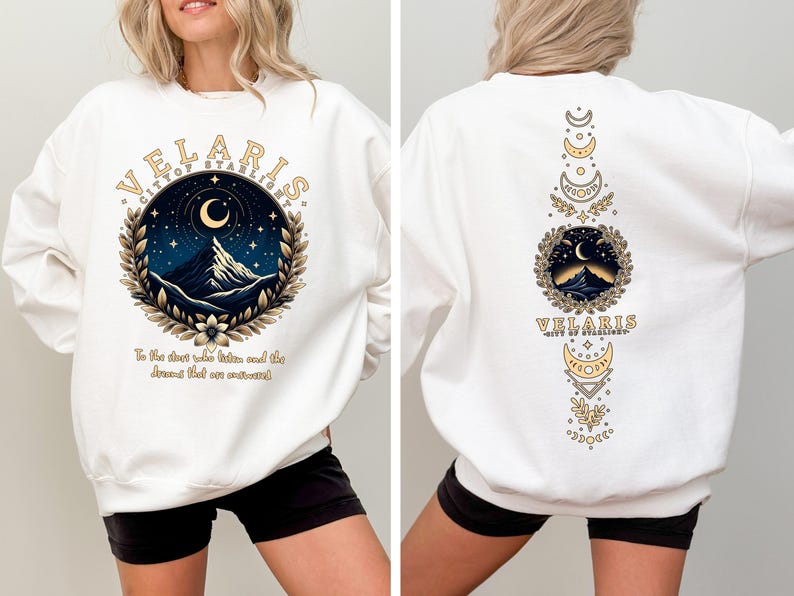 May include: White sweatshirt with a graphic print of a mountain range, moon, and stars in a circle with the text "Velaris City of Starlight" and the text "To the stars who listen and the dreams that are answered". The back of the sweatshirt has a vertical design with a mountain range, moon, and stars in a circle with the text "Velaris City of Starlight" and a series of crescent moons.