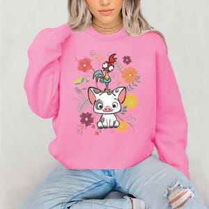 May include: Pink sweatshirt featuring a cartoon image of a pig and a rooster with floral accents.