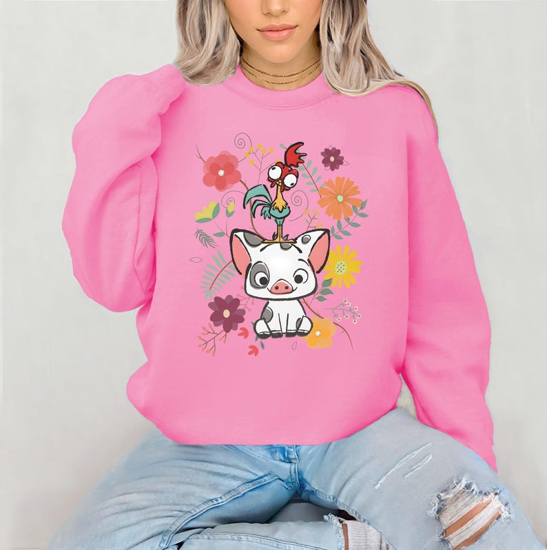 May include: Pink sweatshirt featuring a cartoon image of a pig and a rooster with floral accents.